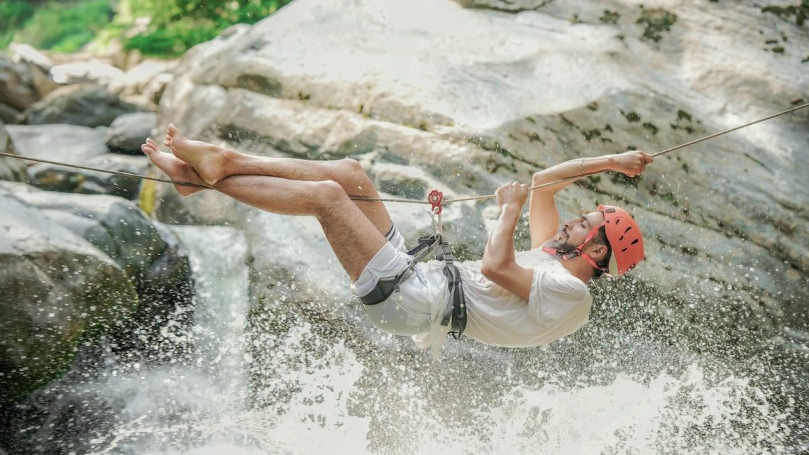 Exciting outdoor adventure of a man ziplining over a waterfall in Srinagar.